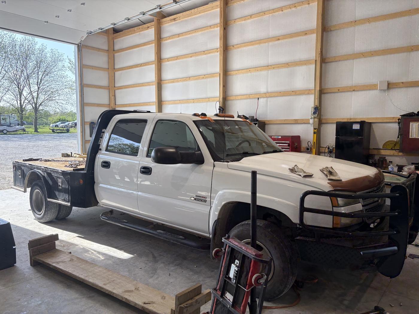 A white dually pickup with a flatbed inside the workshop bay, part way through a job